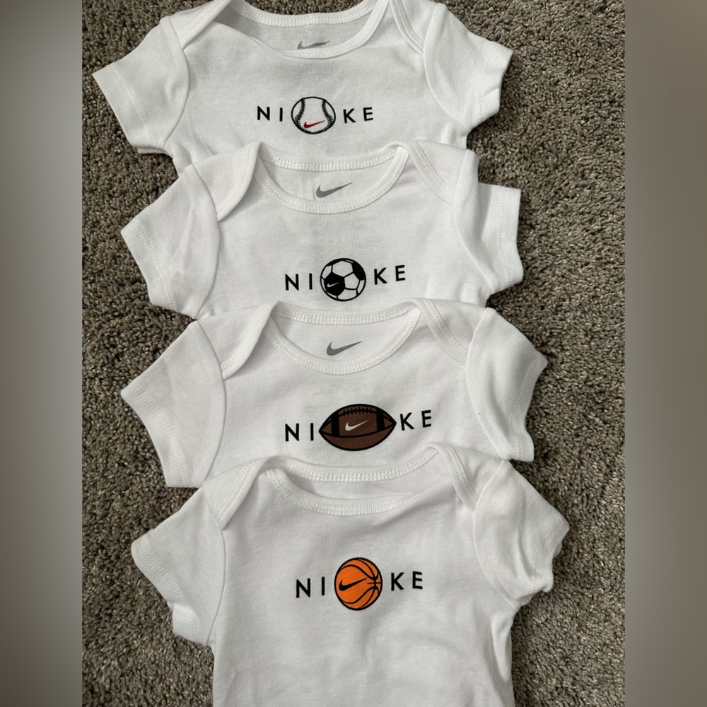 Nike white onesies with various sport balls. Size 6 months. New without tags.